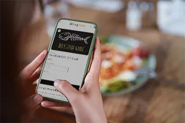 A supporter using a digital fundraising gift card on their smartphone at Bonefish Grill.